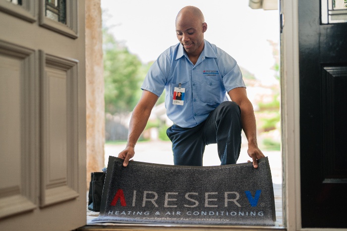 aire serv employee laying rug in doorway